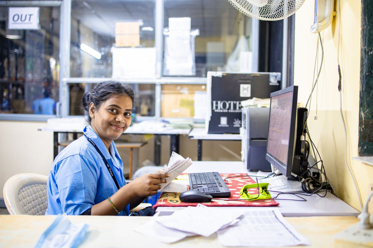 Friendly office worker in a modern workspace, smiling while handling documents at her desk.