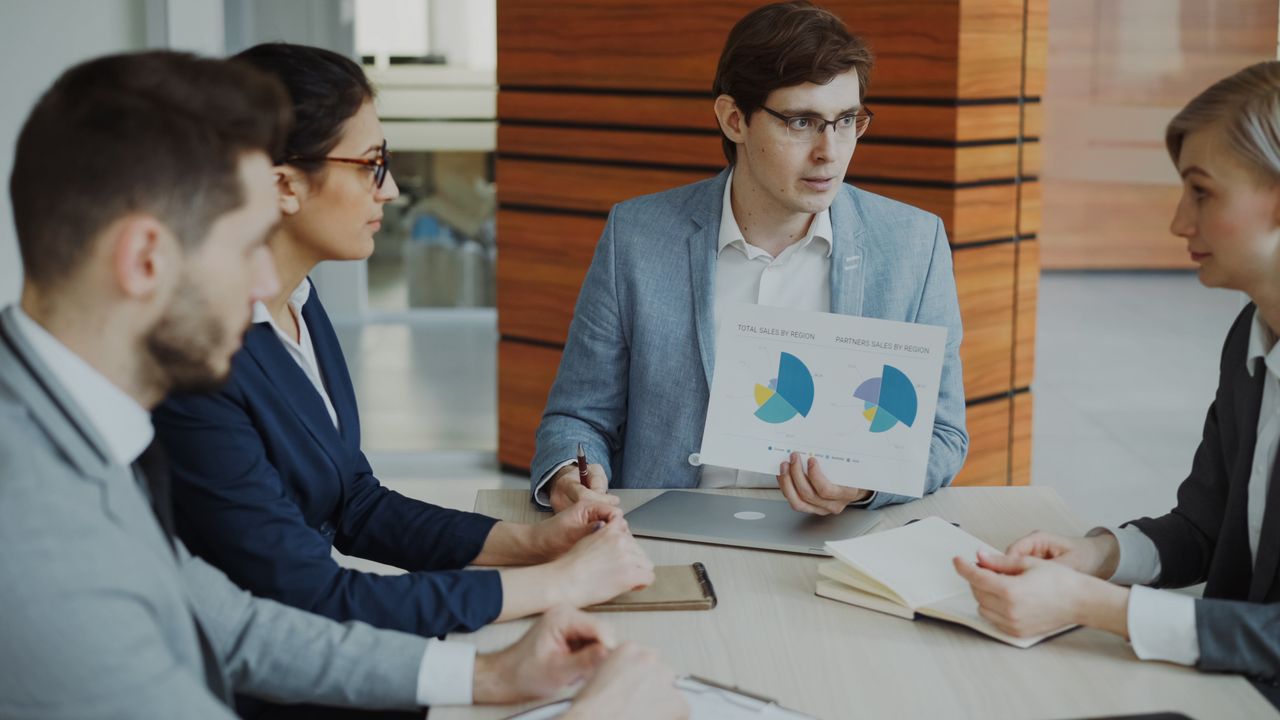 Group of professionals discussing charts during a business meeting.