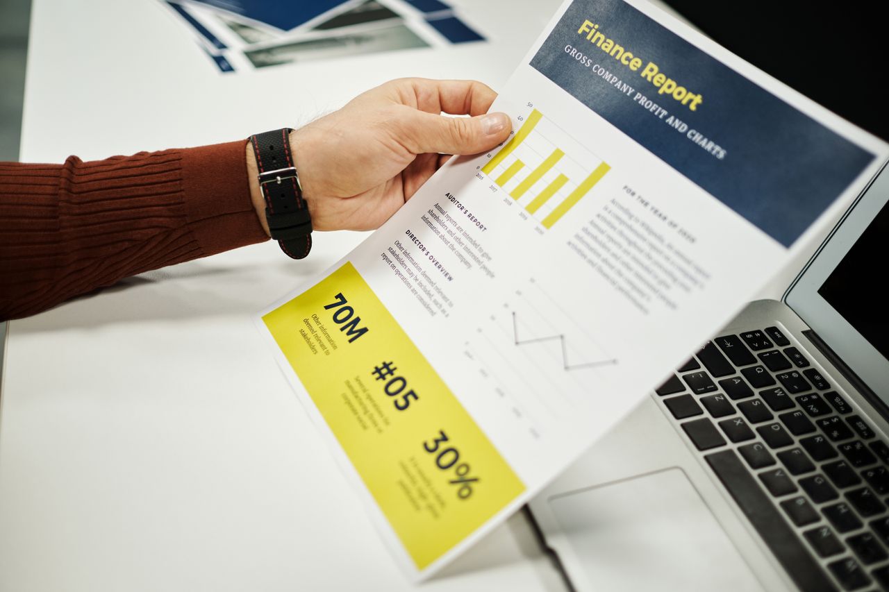 Person analyzing finance report with graphs at desk, ideal for business concepts.
