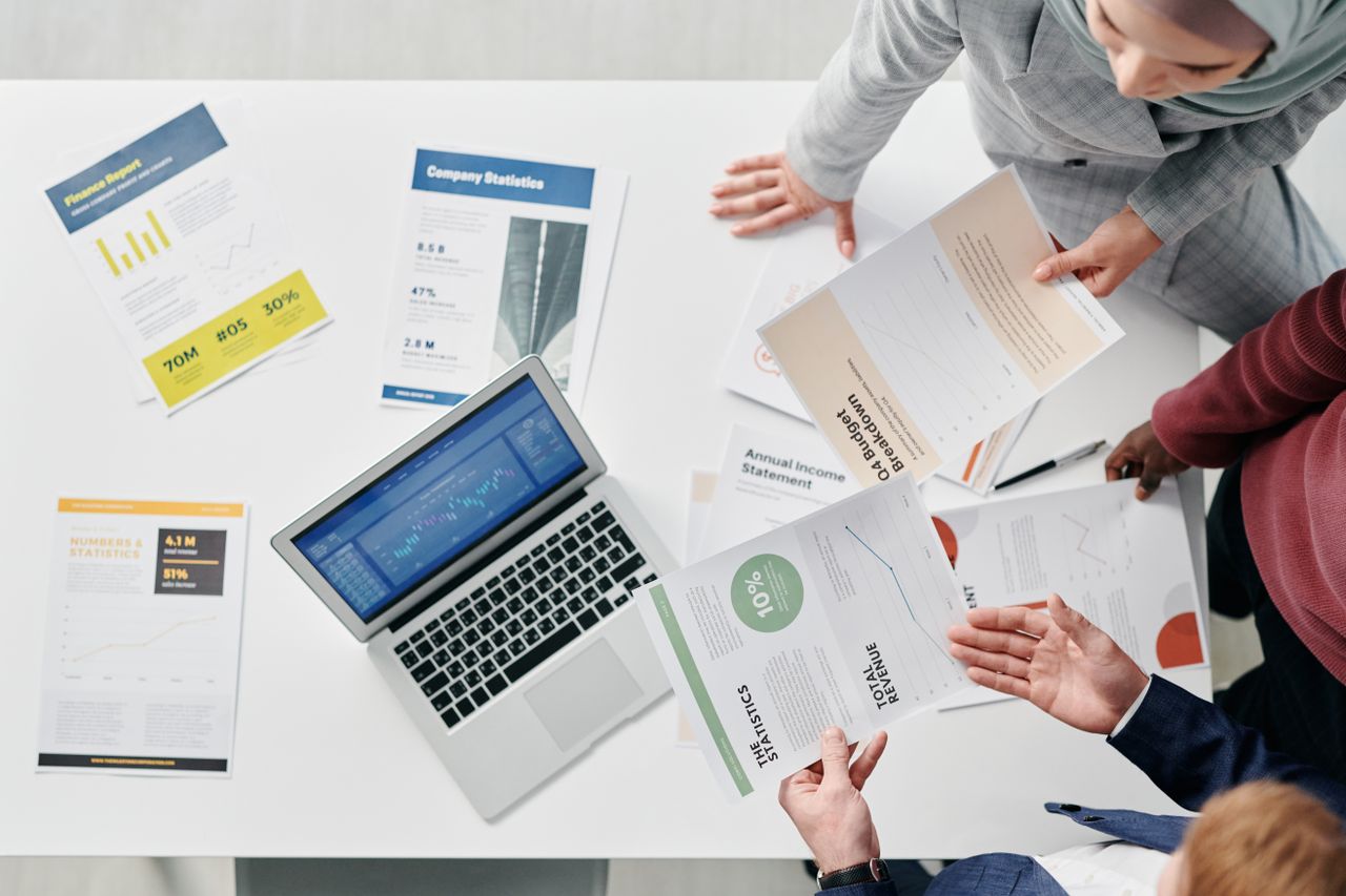 Top view of a professional office meeting with documents and laptop on the table.