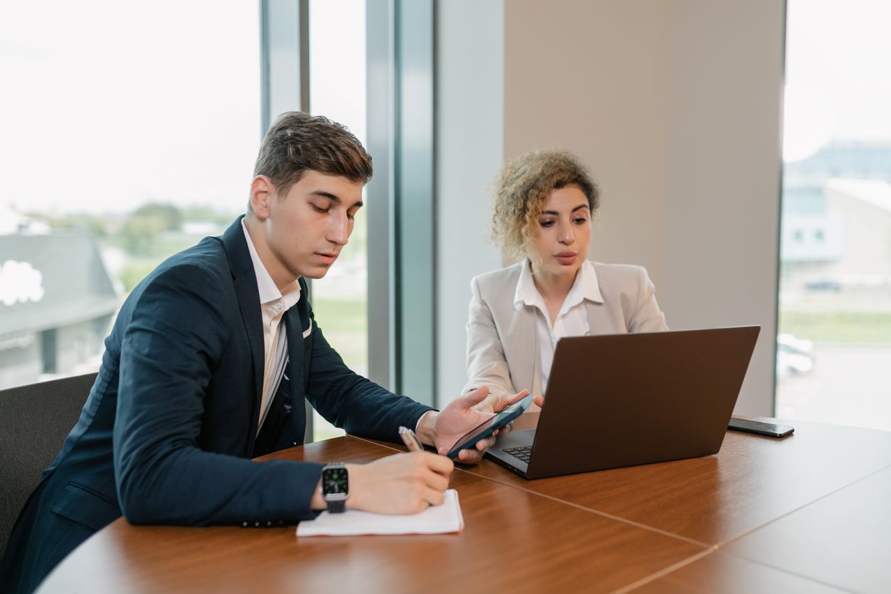 Corporate professionals collaborating with laptop and phone in a modern office setting.